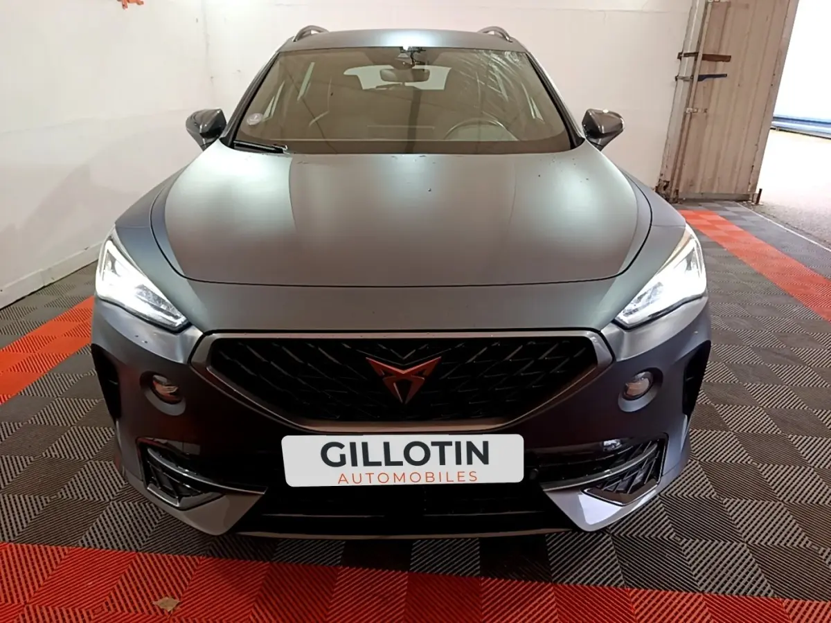 Vue avant d'une CUPRA Formentor gris foncé avec calandre noire et phares LED allumés dans un garage.