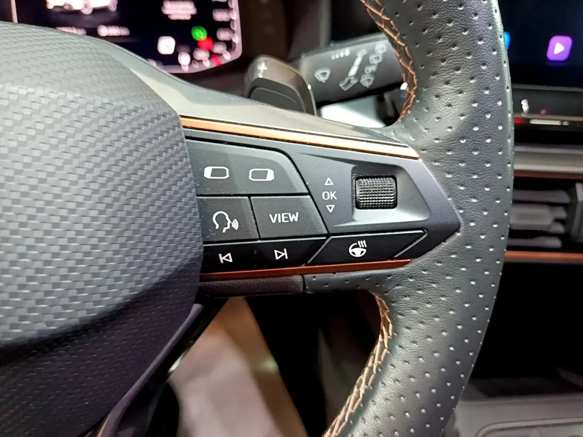 Gros plan sur le volant cuir perforé gris foncé de la CUPRA Formentor 2024 avec commandes multifonctions et finition alu.