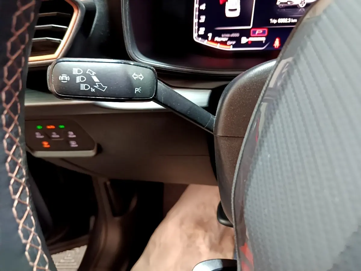 Gros plan sur le commodo gauche du volant en cuir et alu du CUPRA Formentor gris foncé, avec tableau de bord numérique en arrière-plan.