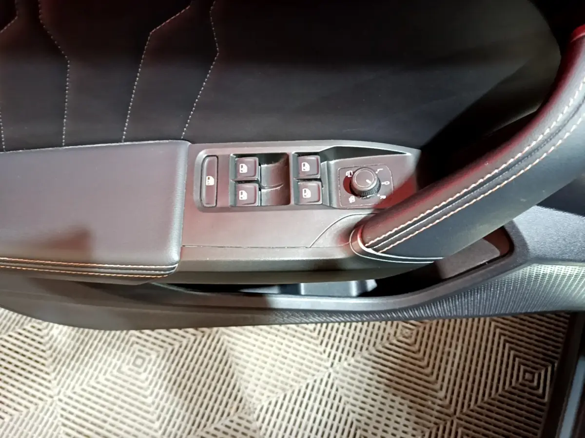 Gros plan sur la commande des vitres et rétroviseurs côté gauche en cuir noir avec surpiqûres blanches dans une CUPRA Formentor gris foncé.