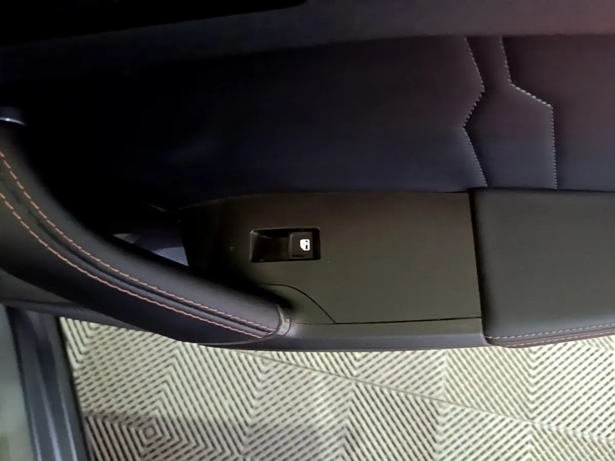 Détail de la portière côté gauche du CUPRA Formentor gris foncé avec bouton de verrouillage et surpiqûres orange.