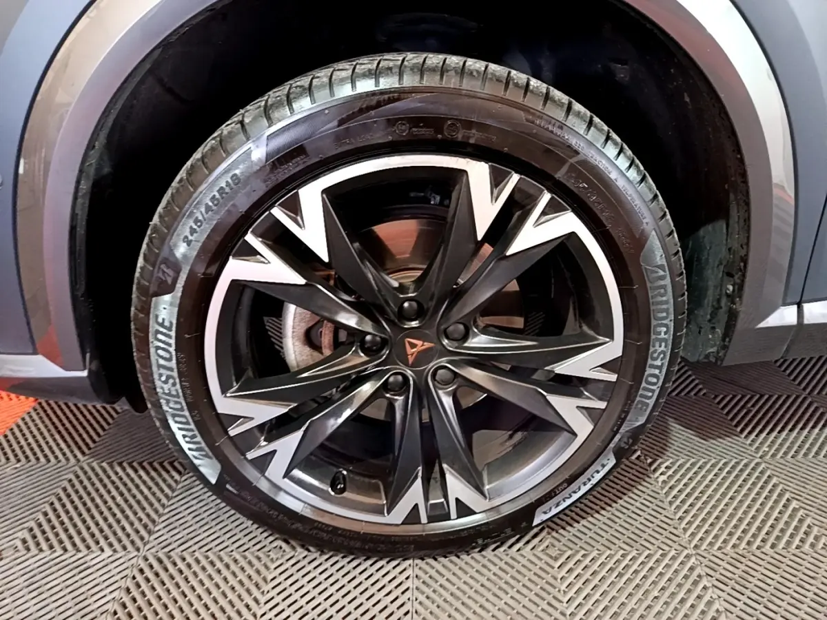 Gros plan sur la roue avant droite du CUPRA Formentor gris foncé, jante alliage noire et argentée au design dynamique.