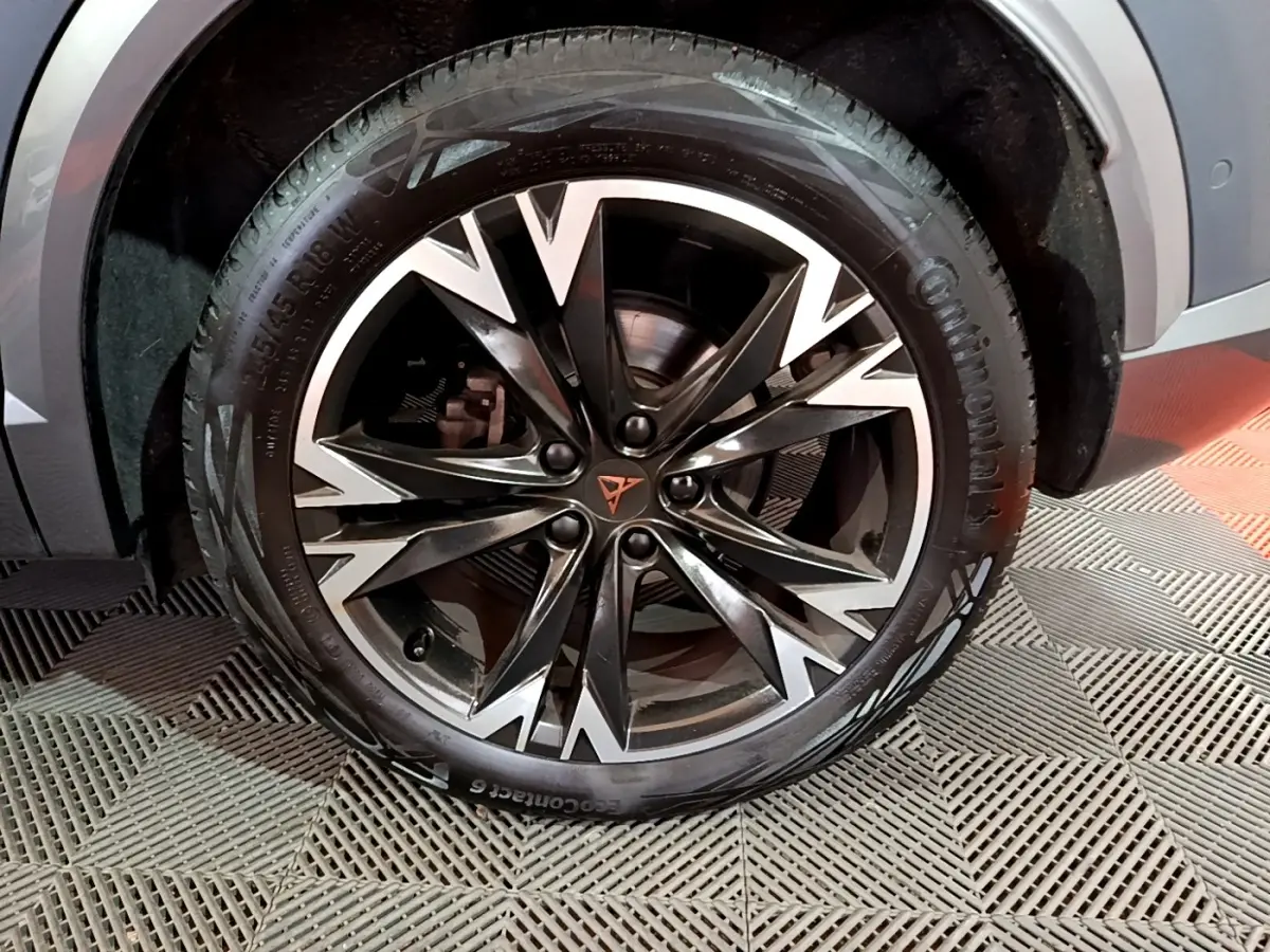 Gros plan sur la roue avant droite d'une CUPRA Formentor gris foncé avec jante alliage noire et argentée au design anguleux.