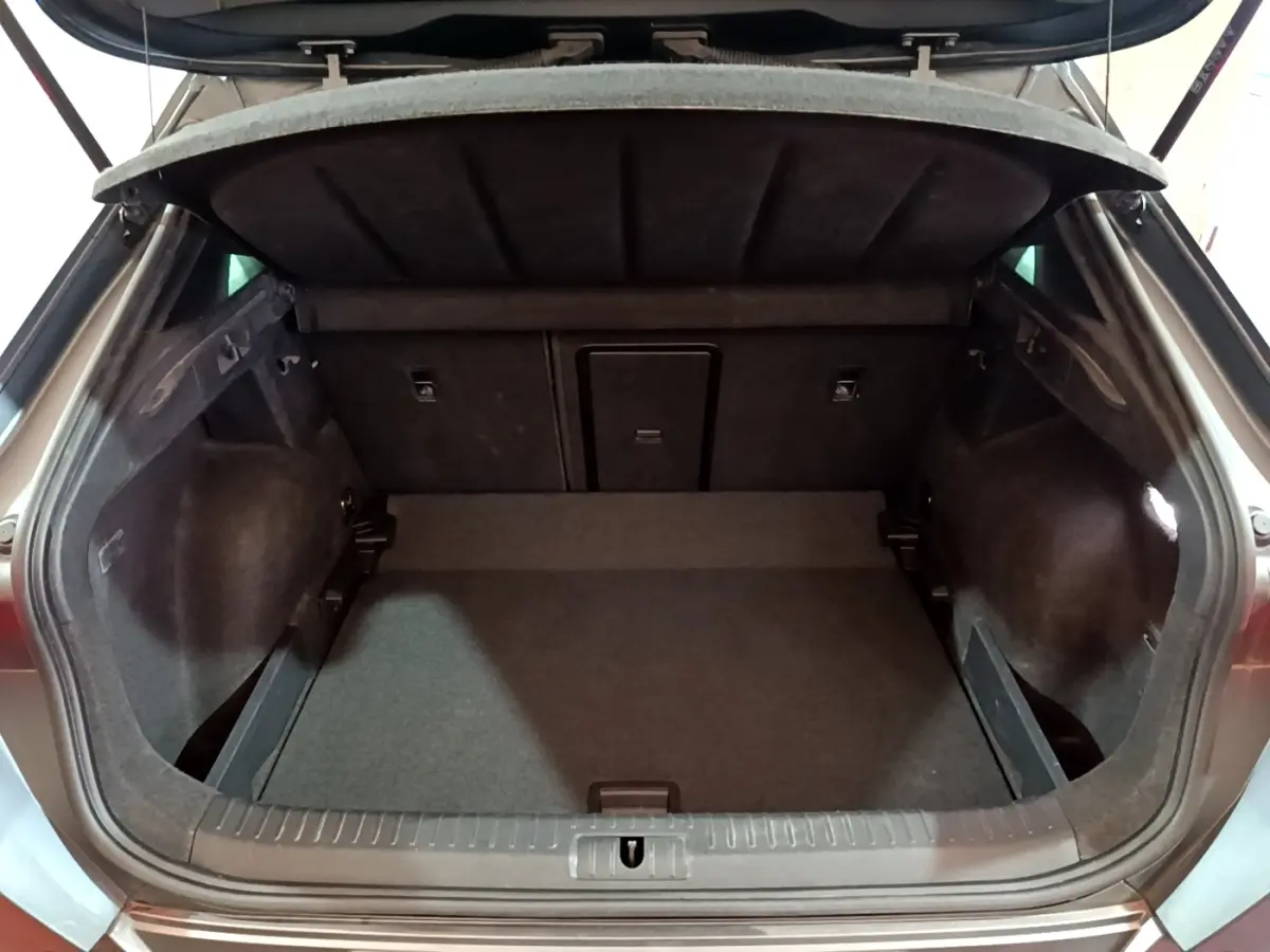 Coffre ouvert vu de l'arrière d'un CUPRA Formentor gris foncé, montrant un espace de chargement propre et spacieux.