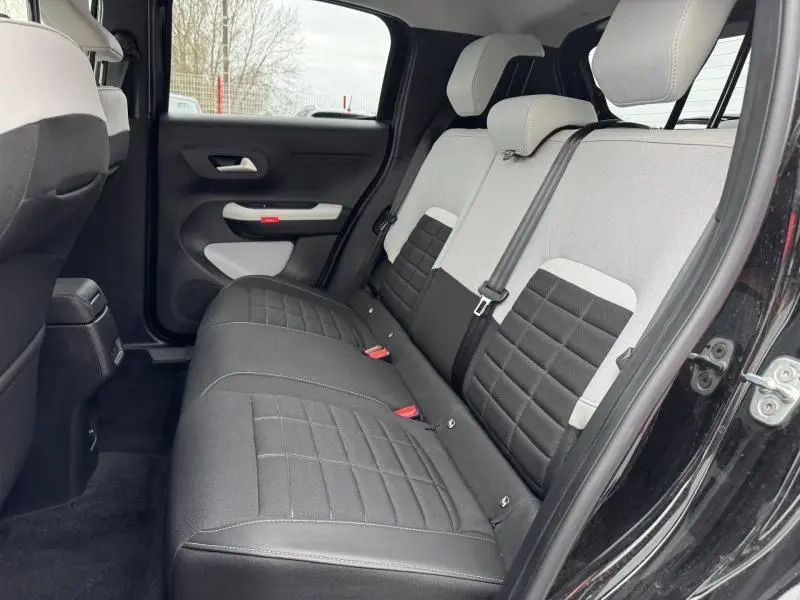 Vue latérale gauche de l'intérieur arrière du Citroën C3 2025 noir Perla Nera avec banquette bicolore noire et grise.