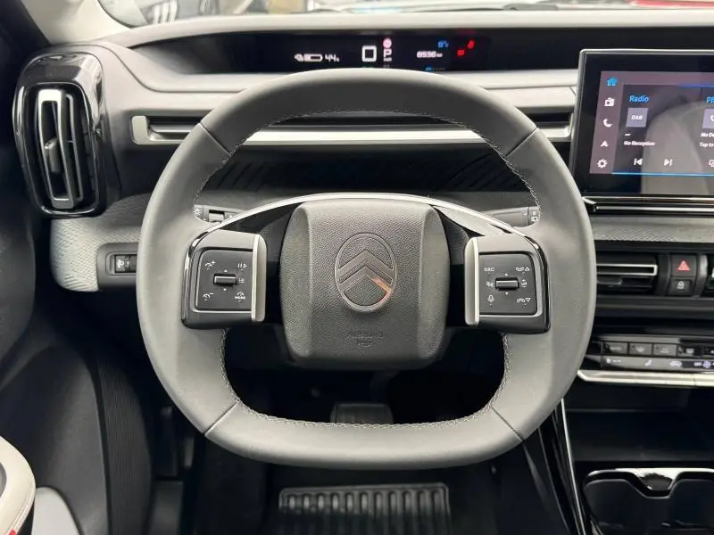 Vue intérieure centrée sur le volant noir de la Citroën C3 électrique 2025 avec tableau de bord numérique et écran tactile.