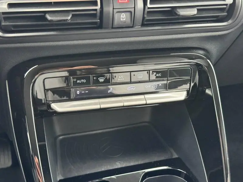 Vue rapprochée de la console centrale noire brillante de la Citroën C3 électrique 2025, avec commandes climatisation tactiles.
