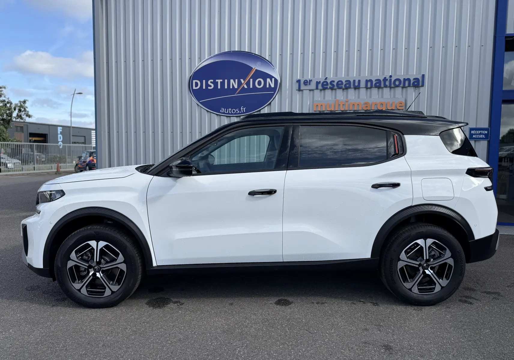 Vue de profil côté gauche d'un Citroën C3 Aircross 2026 blanc banquise avec toit noir, roues alliage et détails noirs contrastants.