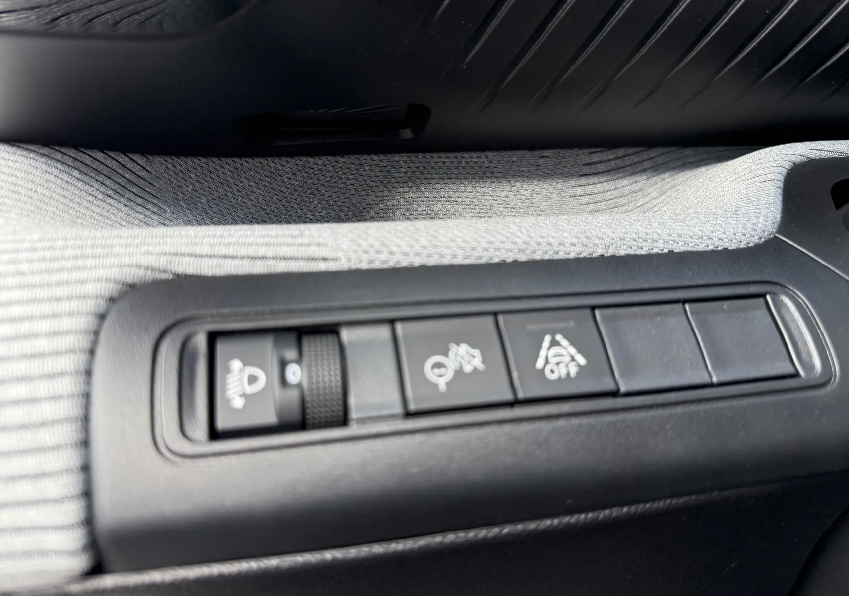 Gros plan sur les commandes noires intégrées dans la garniture grise du côté conducteur d’un Citroën C3 Aircross blanc banquise toit noir.