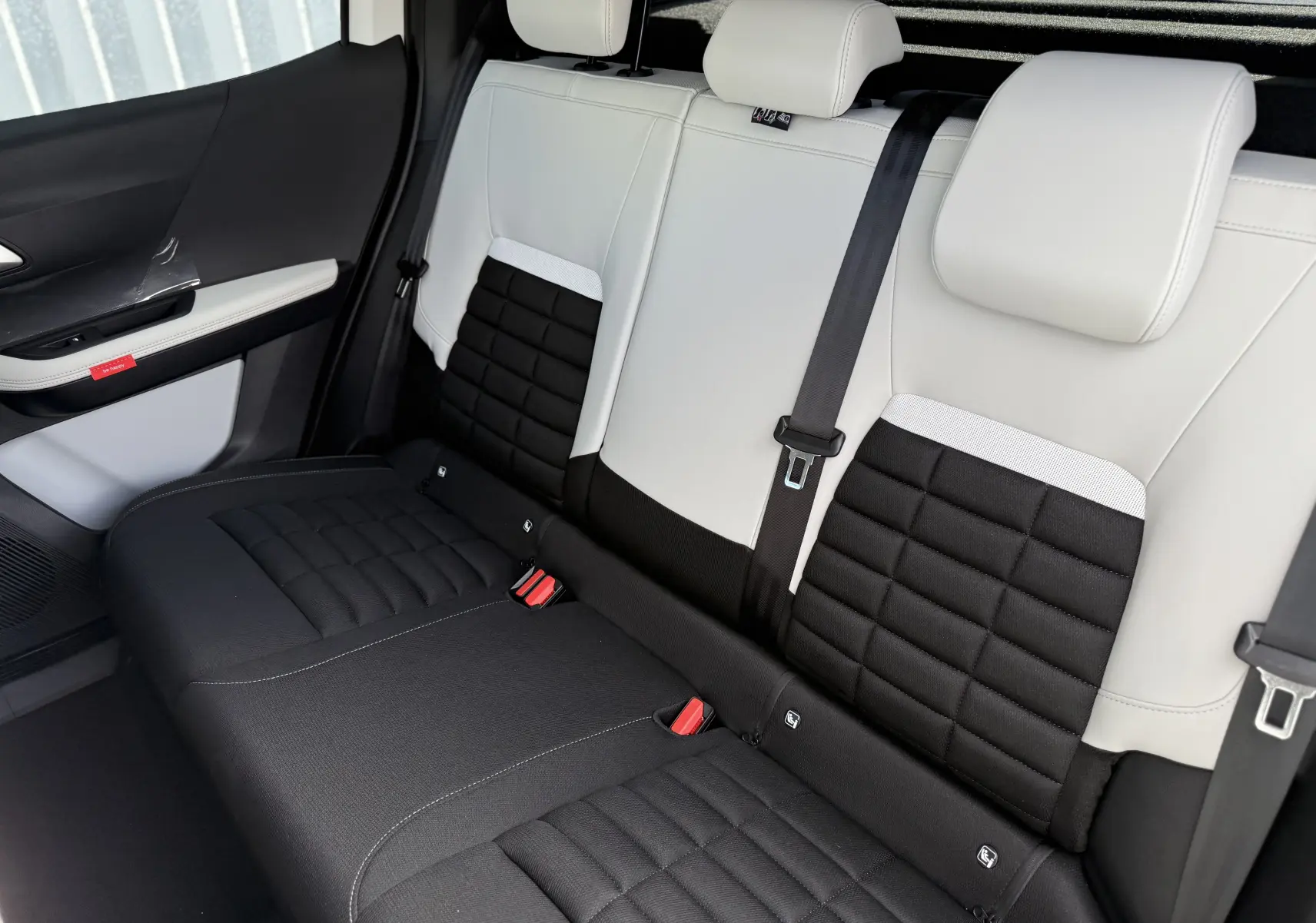 Vue intérieure du siège arrière bi-ton noir et blanc du Citroën C3 Aircross Hybrid 145, avec ceinture de sécurité centrale visible.