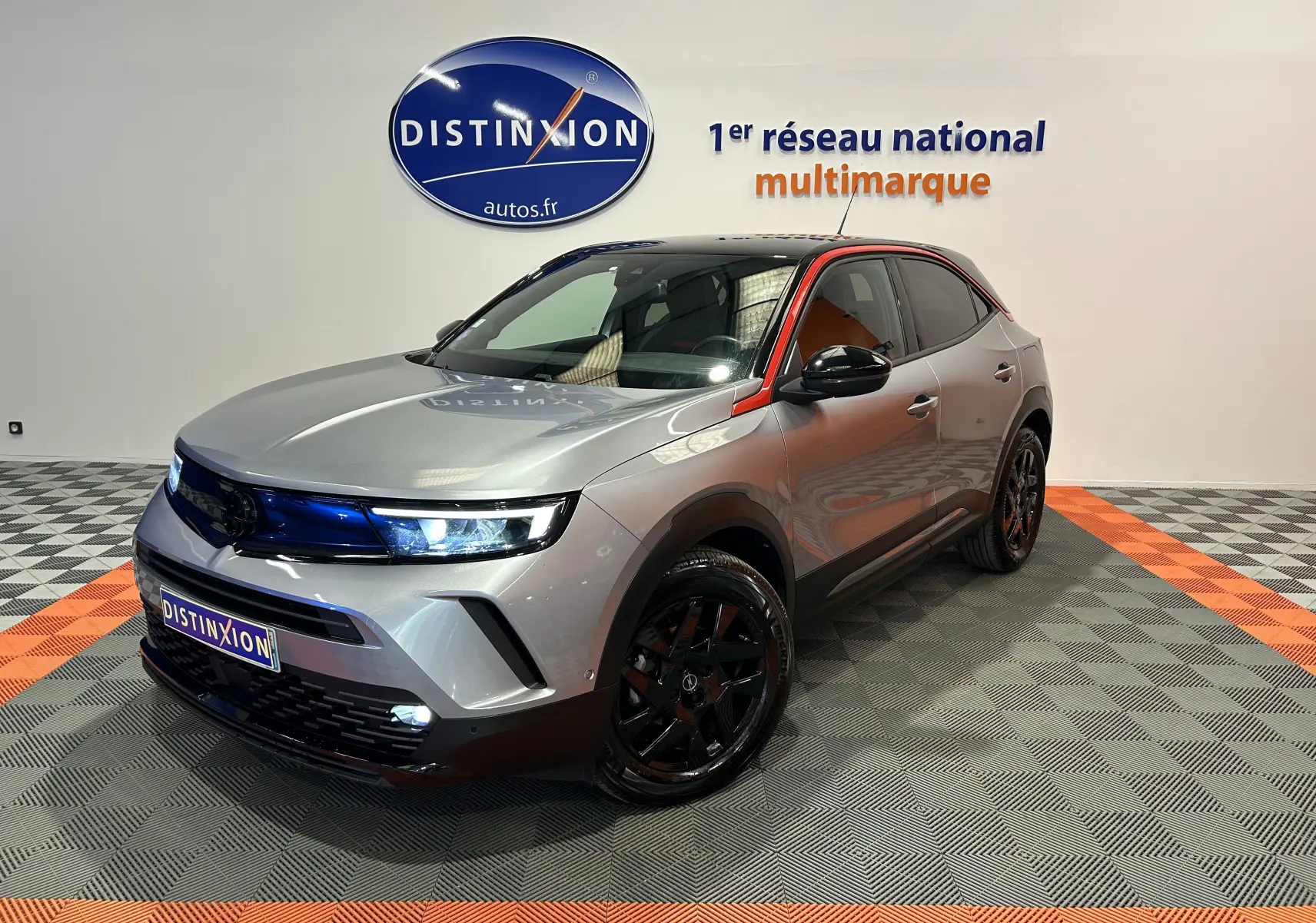 Opel Mokka GS Line gris en 3/4 avant droit, avec jantes noires et barre de toit Thule visible.