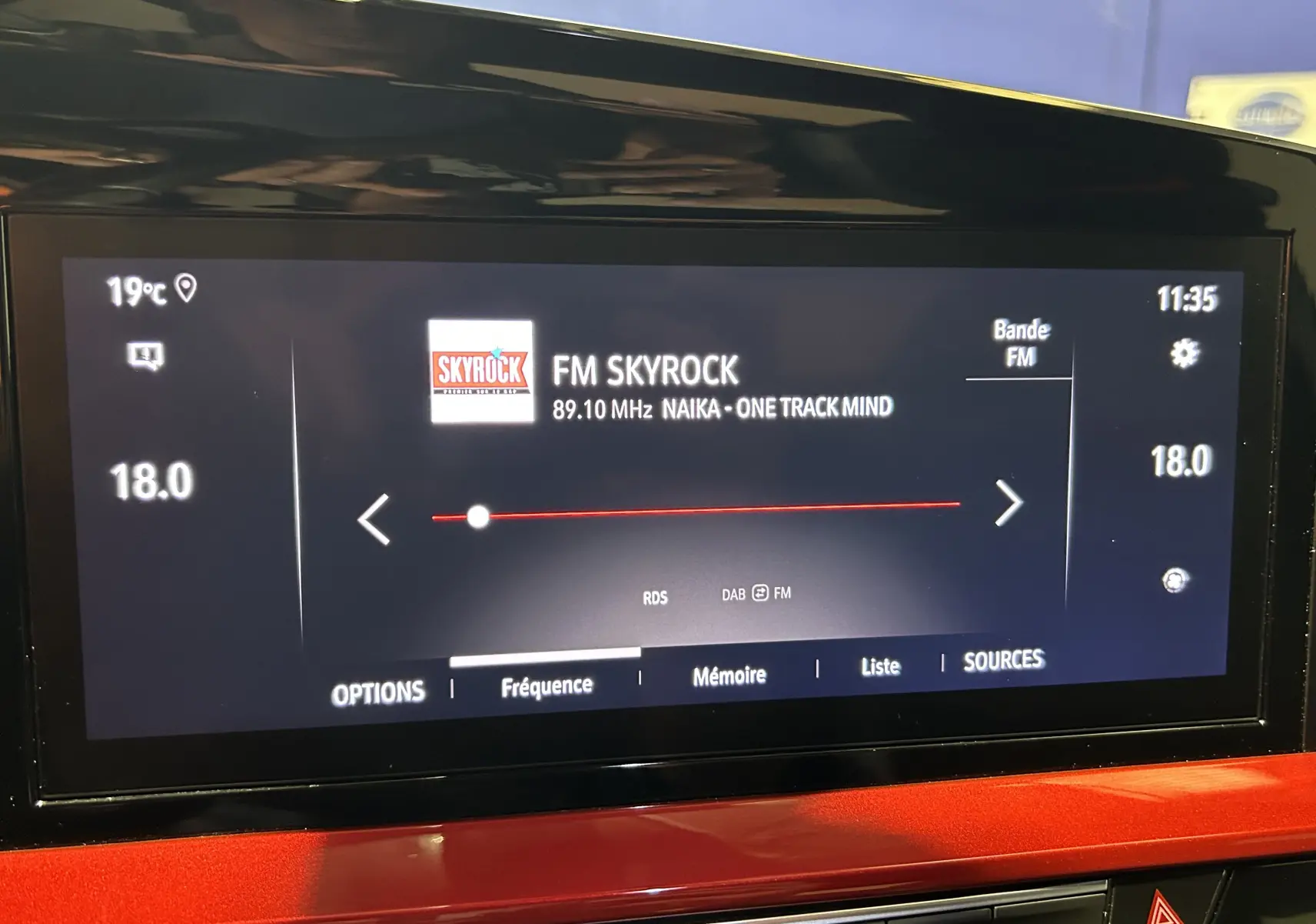 Écran tactile intérieur de l’Opel Mokka GS Line 2022 affichant la radio FM Skyrock, avec tableau de bord rouge visible.