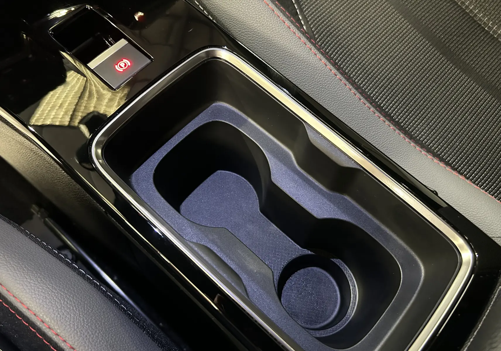 Gros plan sur le porte-gobelets central noir avec contour chromé et surpiqûres rouges des sièges d’un Opel Mokka GS Line.