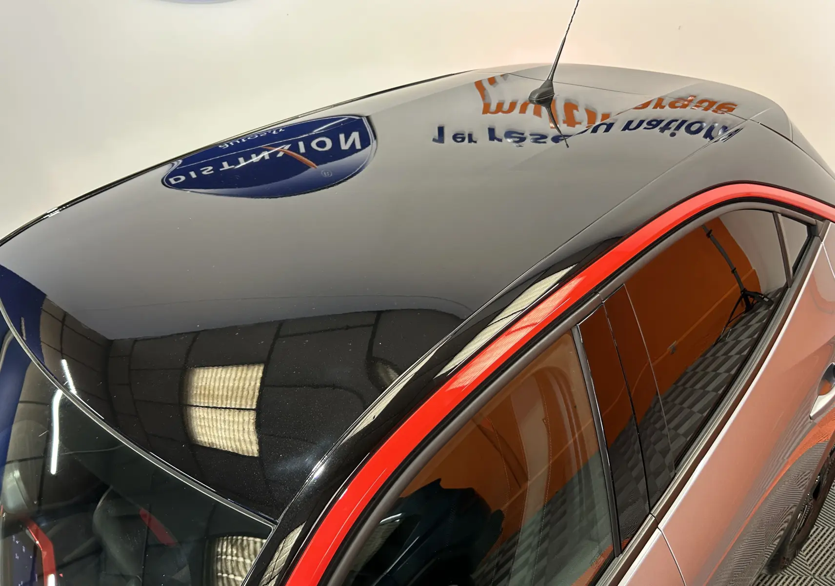Vue en plongée du toit noir brillant avec antenne et contour rouge vif sur Opel Mokka gris, côté droit.