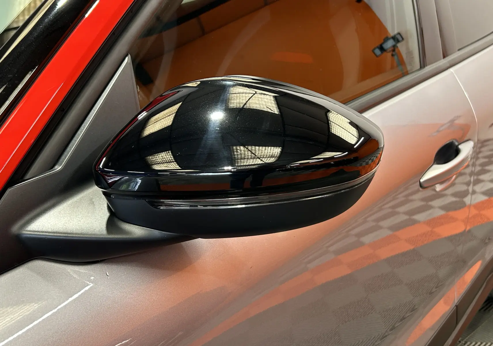Gros plan sur le rétroviseur noir brillant côté gauche d'un Opel Mokka gris avec reflet de lumière intérieure.