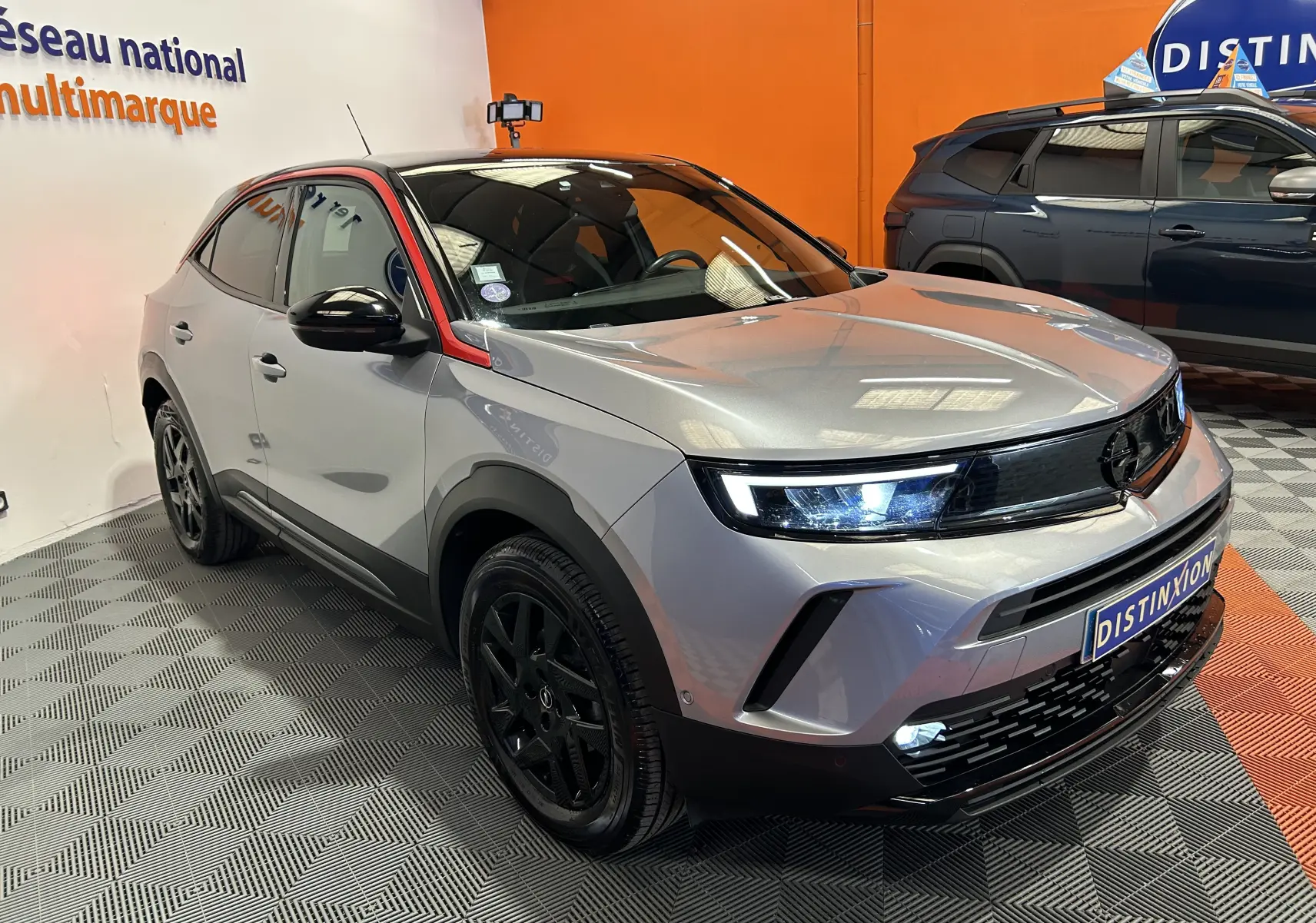 Vue 3/4 avant droite d’un Opel Mokka GS Line gris avec toit noir et jantes noires, en showroom intérieur.