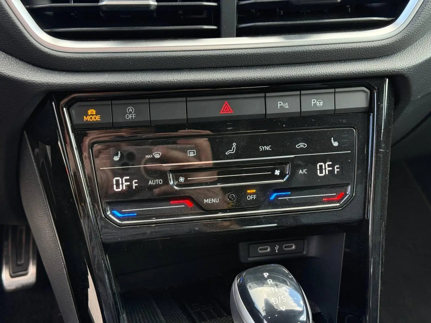 Vue rapprochée de la console centrale du Volkswagen T-Roc 2025, avec commandes climatisation et levier de boîte auto.