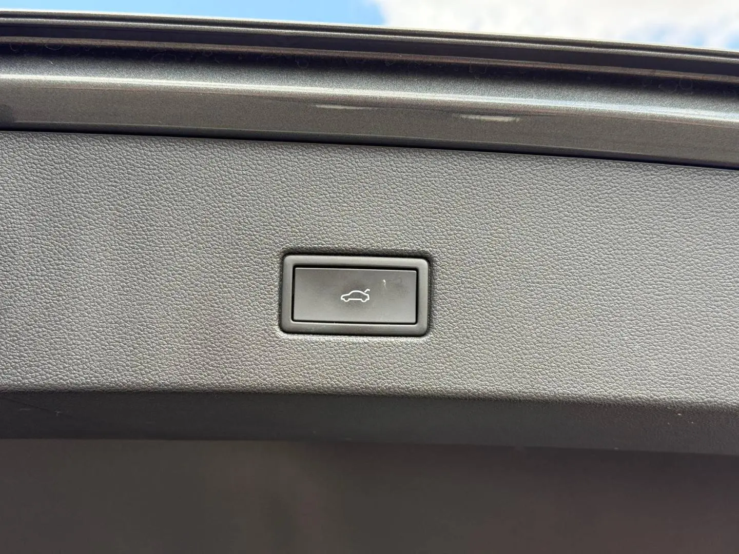 Bouton d'ouverture électrique du coffre sur la garniture intérieure d'un Volkswagen T-Roc gris Indium métallisé.