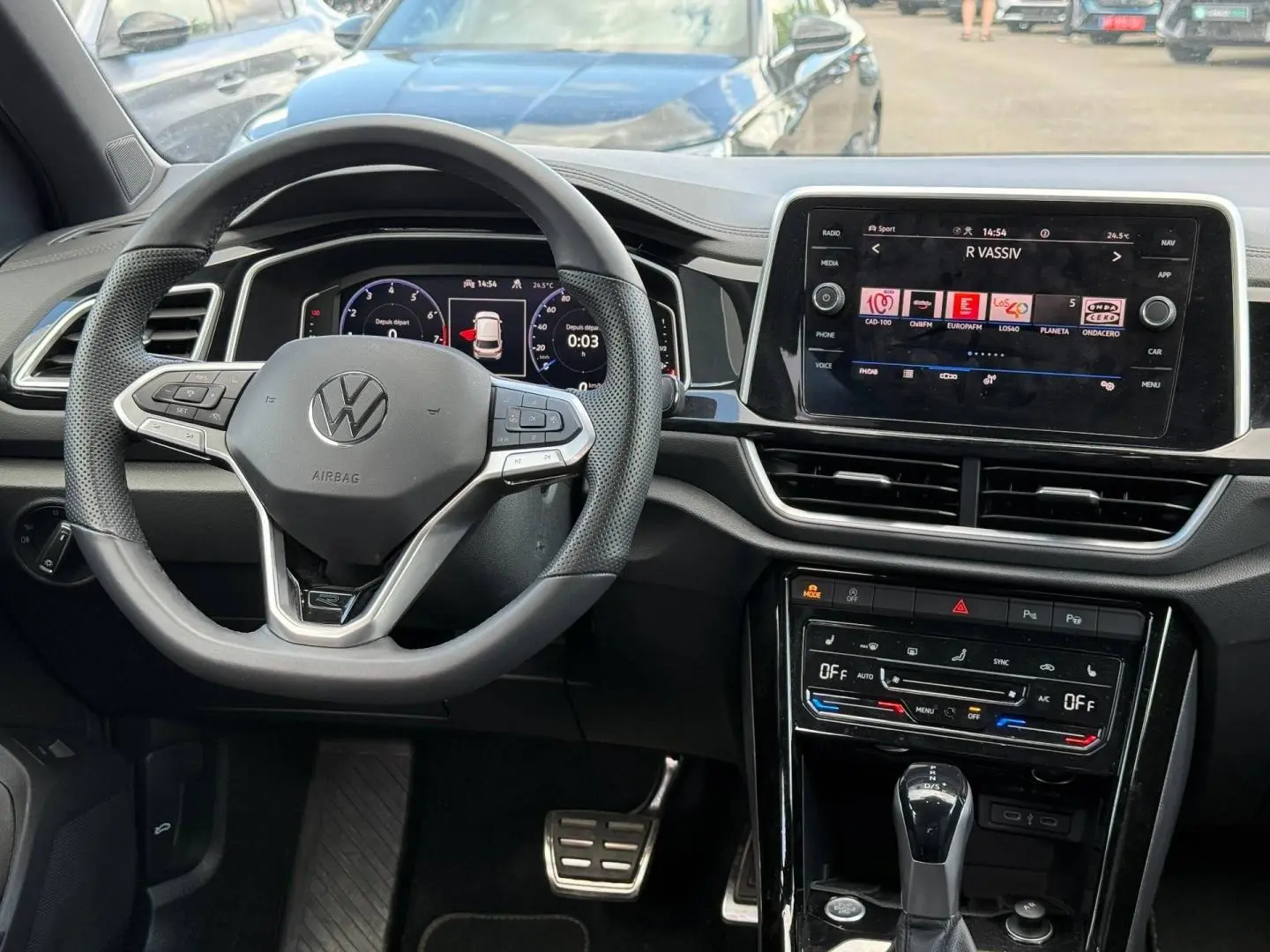 Vue intérieure du tableau de bord du Volkswagen T-Roc 2025 avec volant multifonction et écran tactile central.