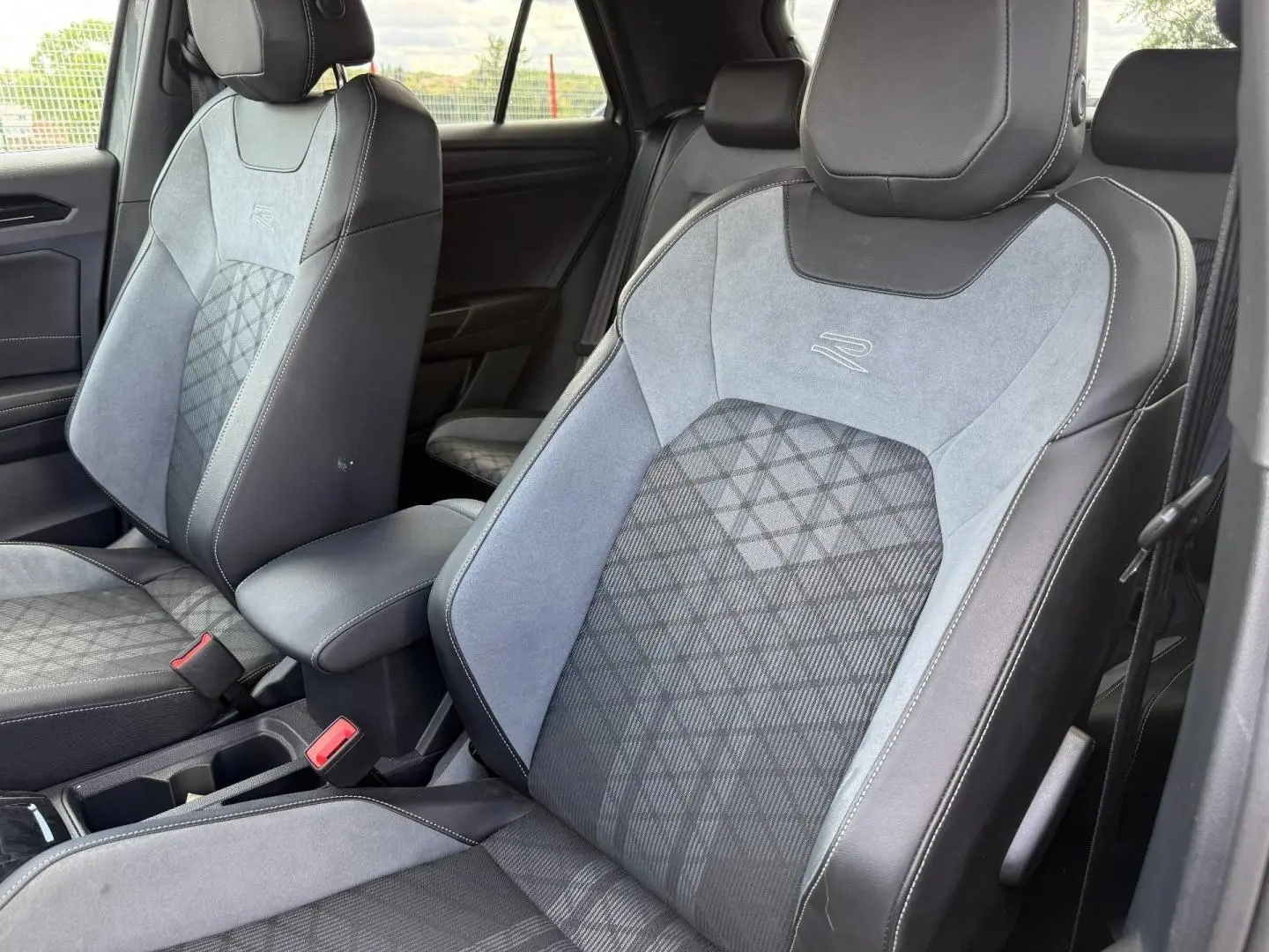 Vue rapprochée des sièges avant gris clair et noir en tissu et cuir avec logo R dans l’habitacle du Volkswagen T-Roc 2025.
