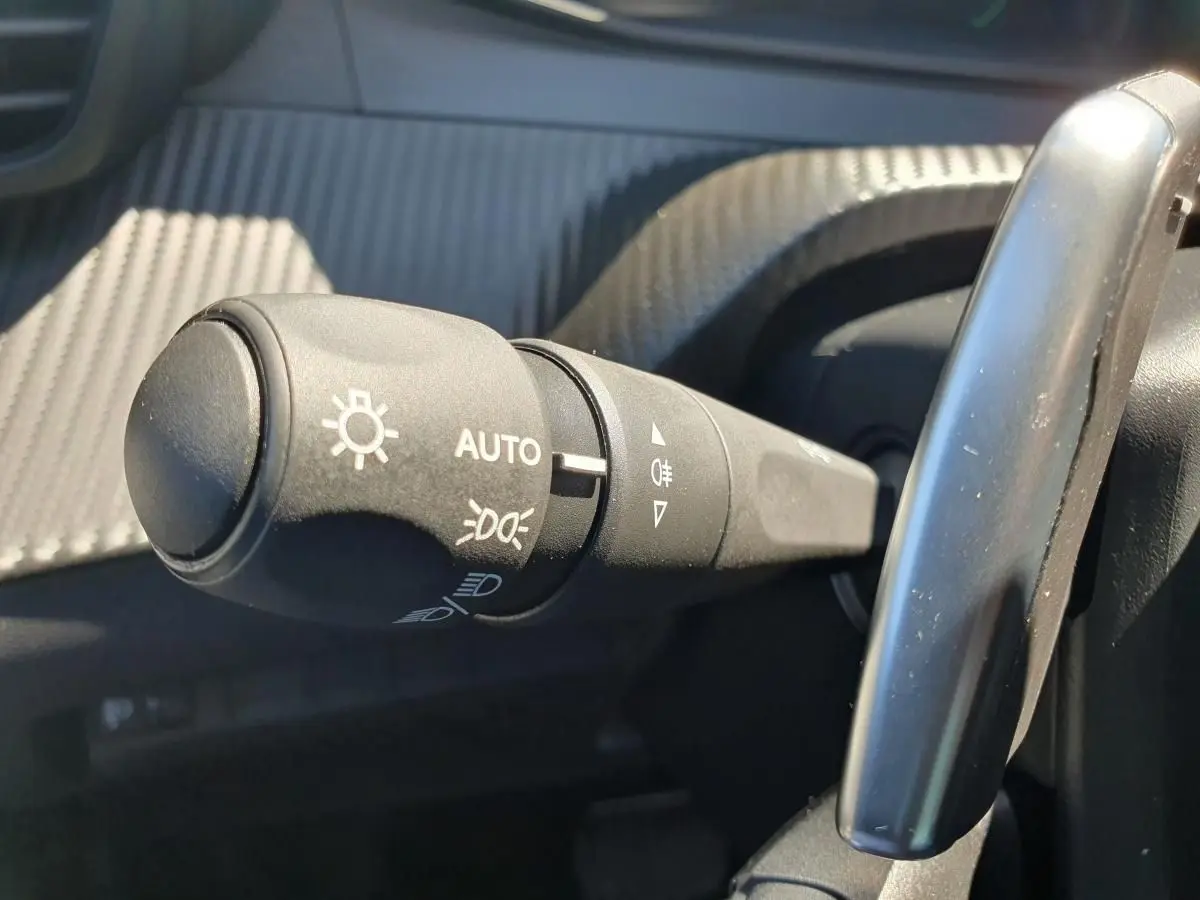 Gros plan sur la commande de phares automatique dans l'habitacle du Peugeot 208 gris Sellenium 2025.