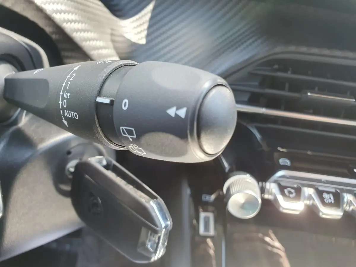 Gros plan sur la commande d’essuie-glace à gauche du volant dans l’habitacle du Peugeot 208 gris Sellenium.