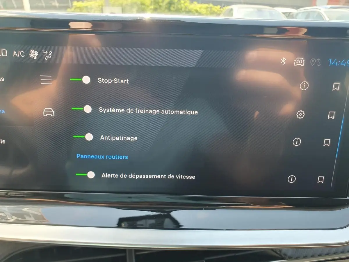 Écran tactile intérieur de la Peugeot 208 1.2 Hybrid 110 Allure affichant les options d’aide à la conduite activées.