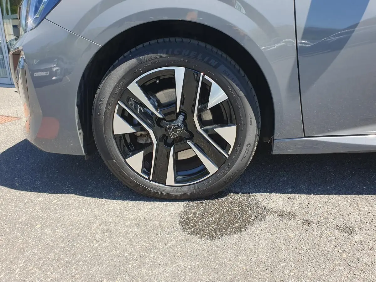 Gros plan sur la roue avant gauche de la Peugeot 208 gris Sélénnium avec jante alliage diamantée bi-tons.