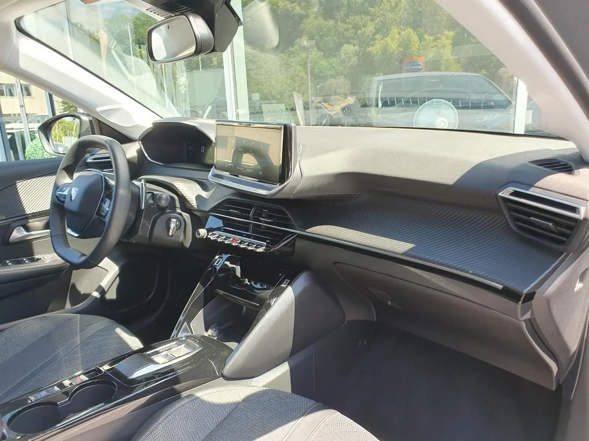 Vue intérieure côté conducteur du Peugeot 208 gris Sellenium, avec tableau de bord moderne et écran tactile central.