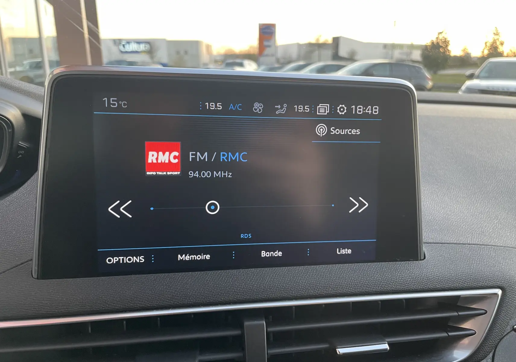 Écran central tactile du tableau de bord du Peugeot 3008 blanc nacré, affichant la radio FM RMC à 94 MHz.