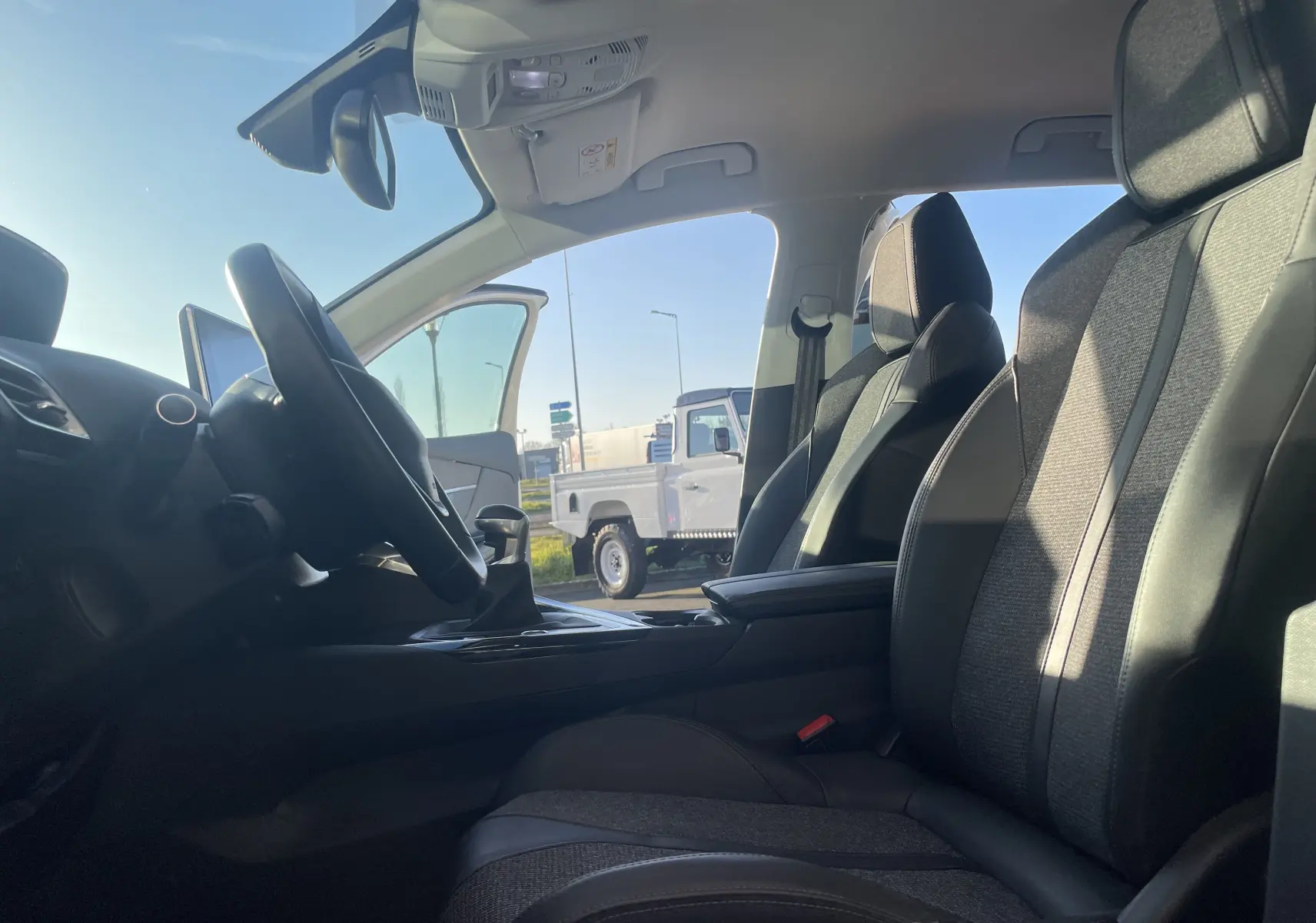 Intérieur du Peugeot 3008 2019, vue côté conducteur montrant les sièges en tissu gris et cuir noir sous lumière naturelle.