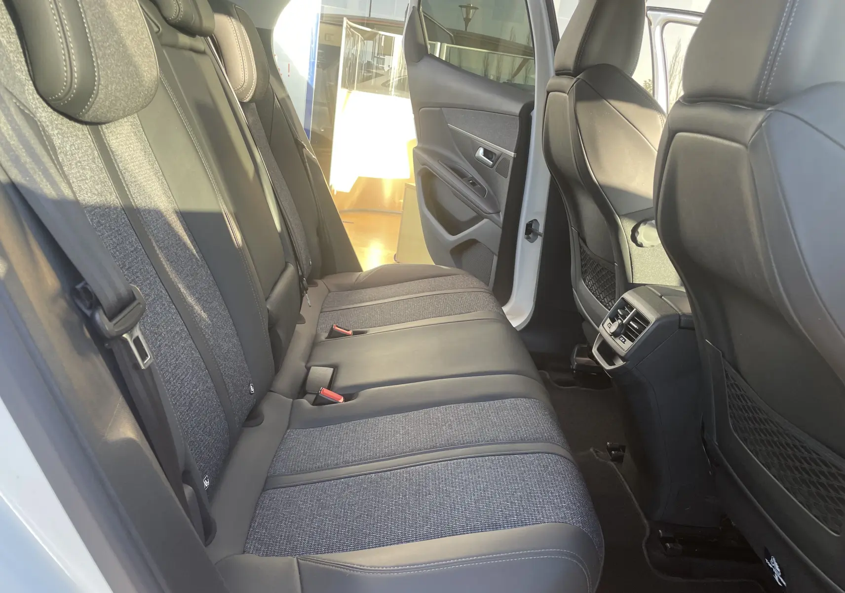 Vue intérieure arrière côté gauche du Peugeot 3008 blanc nacré, sièges arrière en tissu et cuir gris noir avec aérateurs centraux.