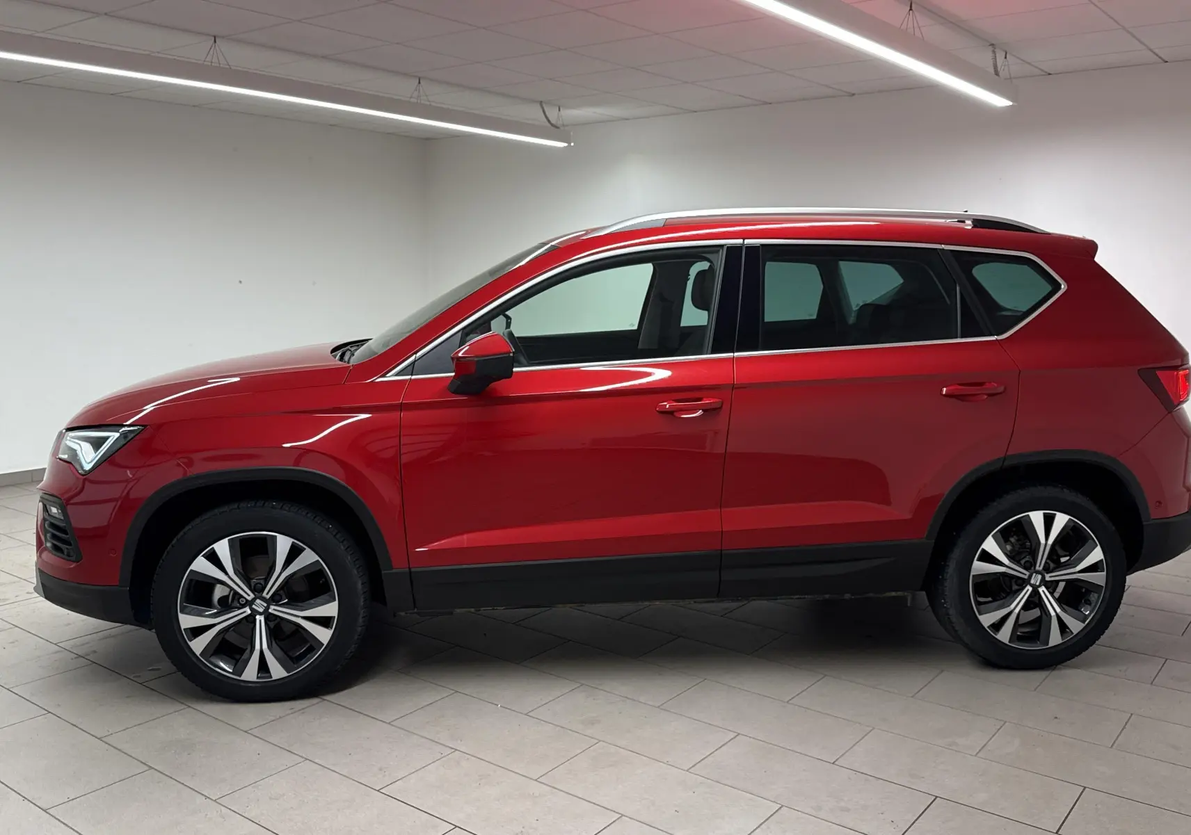 Profil côté gauche du SUV SEAT Ateca 2024 en rouge velvet, avec jantes alliage et toit noir.