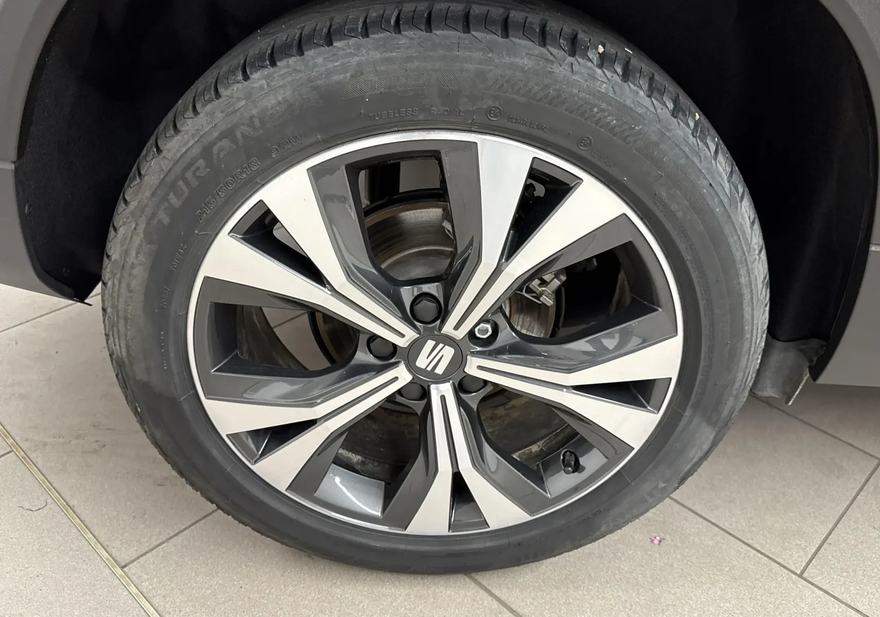 Gros plan sur la roue avant droite du SEAT Ateca rouge velvet, mettant en valeur la jante alliage bicolore.