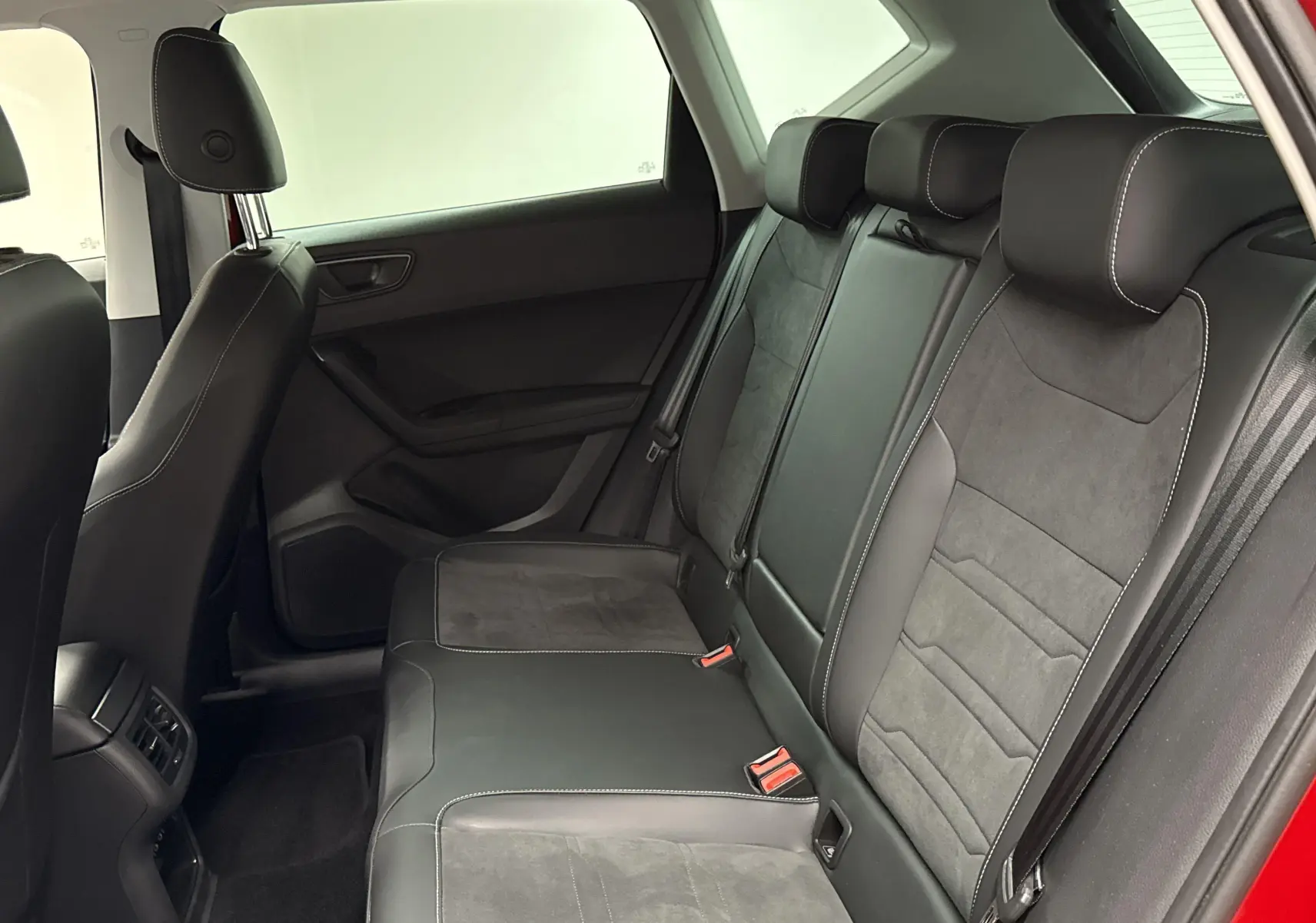 Vue intérieure arrière côté droit du SEAT Ateca 2024 rouge velvet, montrant les sièges en cuir noir avec surpiqûres blanches.