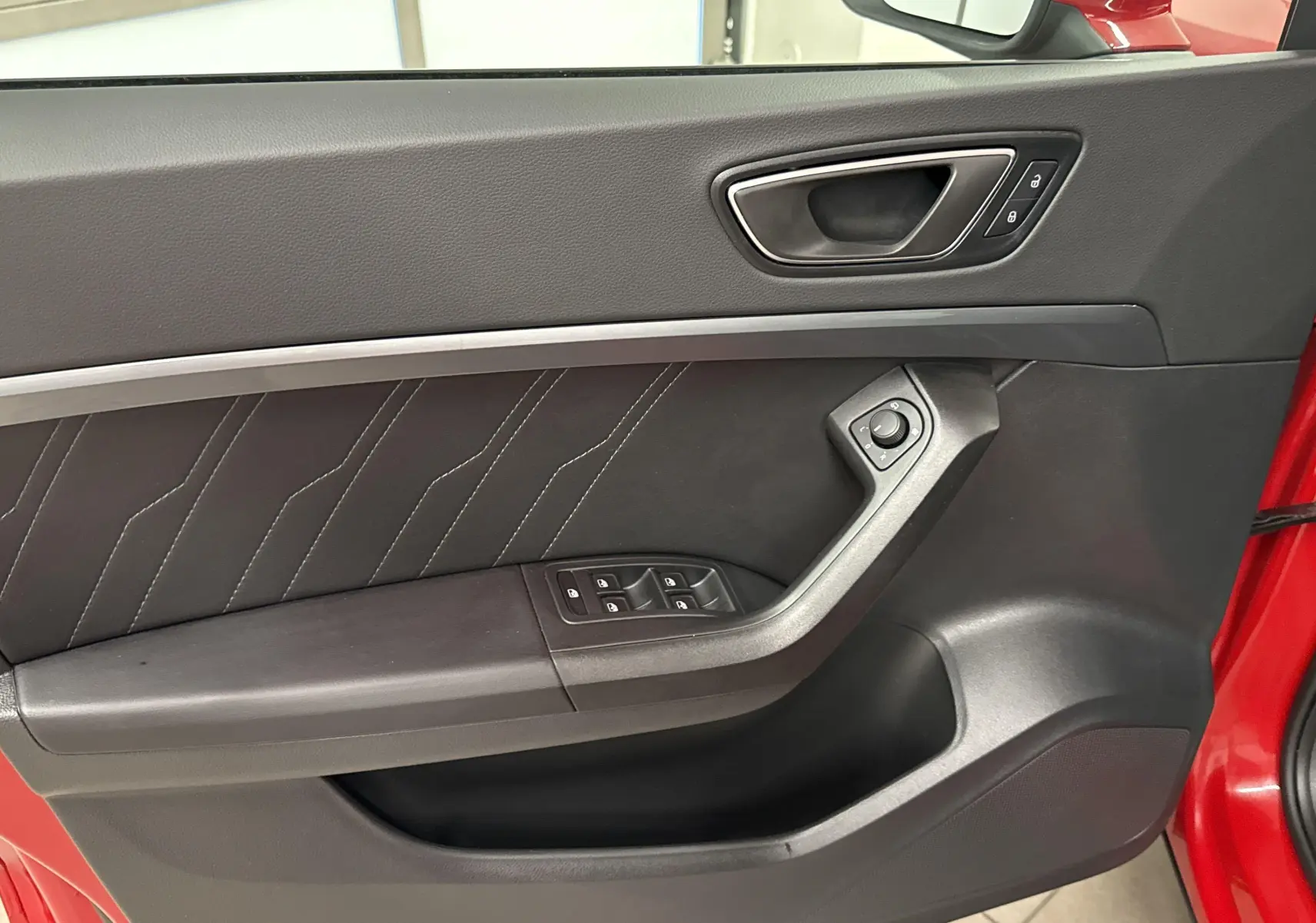 Gros plan sur la porte avant gauche rouge velvet du SEAT Ateca 2024 avec commandes de vitres et poignée intégrée.