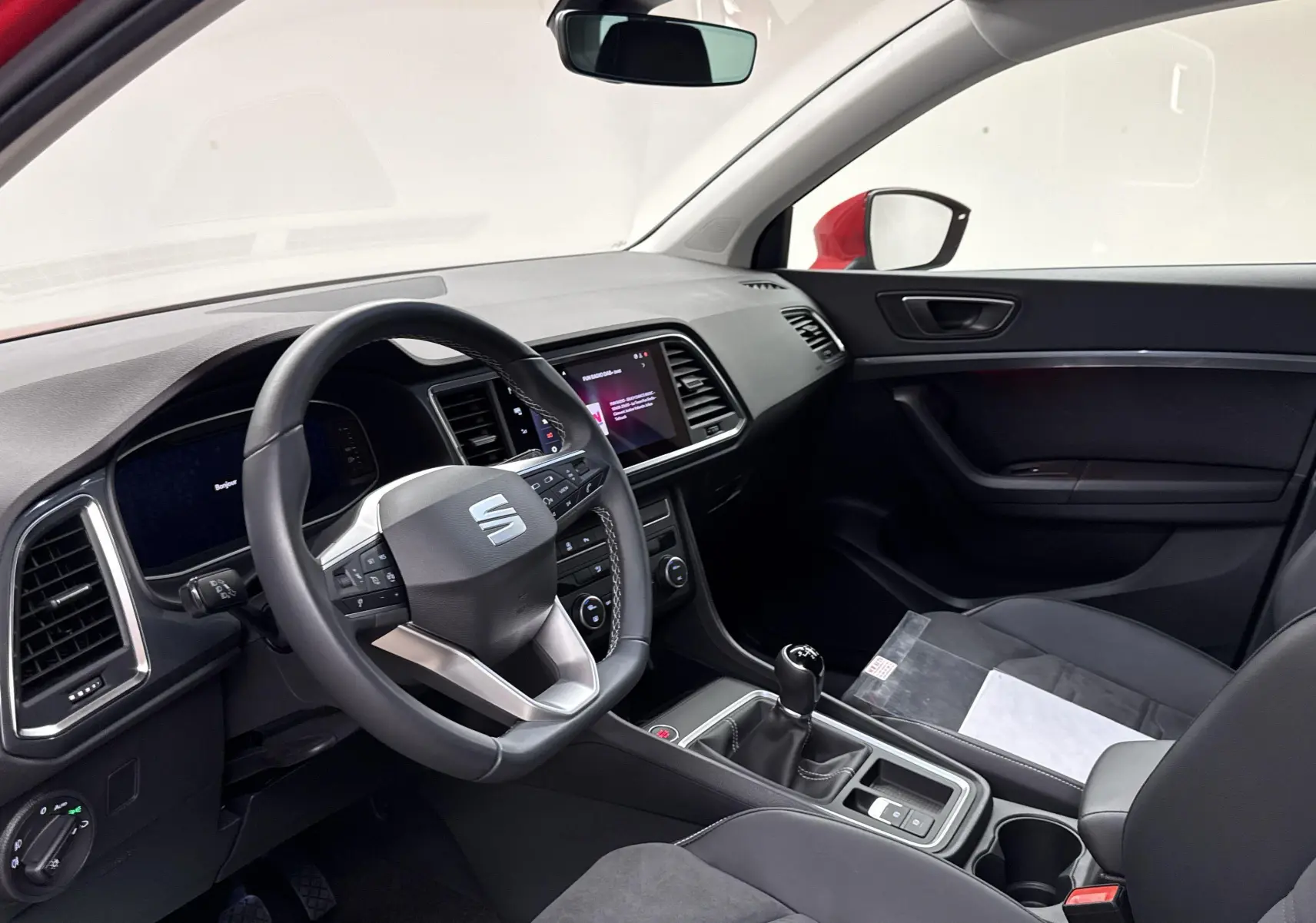 Intérieur avant droit du SEAT Ateca rouge velvet 2024, volant multifonction et levier de vitesse manuel visibles.