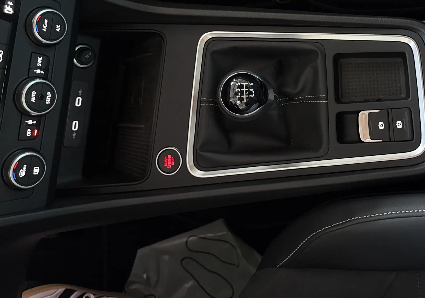 Gros plan sur la console centrale noire du SEAT Ateca 2024 avec levier de vitesse manuel et bouton start/stop rouge.