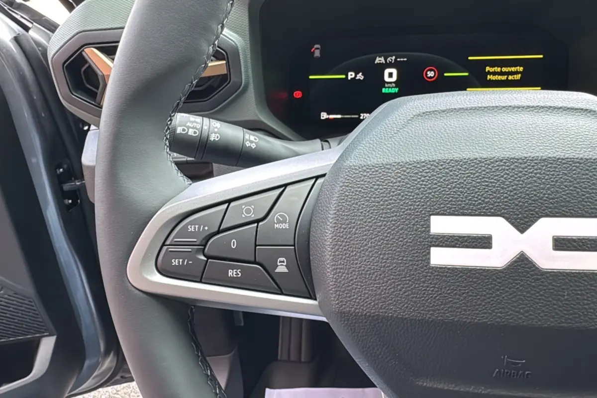 Gros plan sur le volant cuir du Dacia Bigster Hybrid 155 Extreme Plus gris schiste, avec commandes multifonctions et tableau de bord digital.