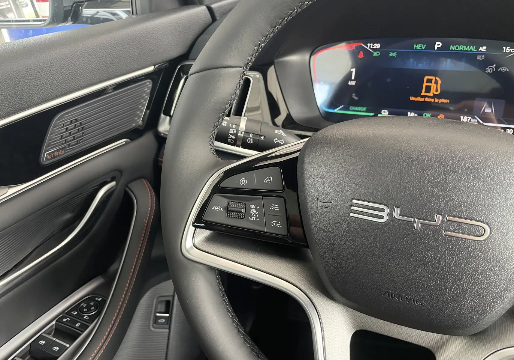 Vue rapprochée du volant noir et du tableau de bord numérique du BYD SEAL U 2026 avec commandes multifonctions et haut-parleur Infinity.