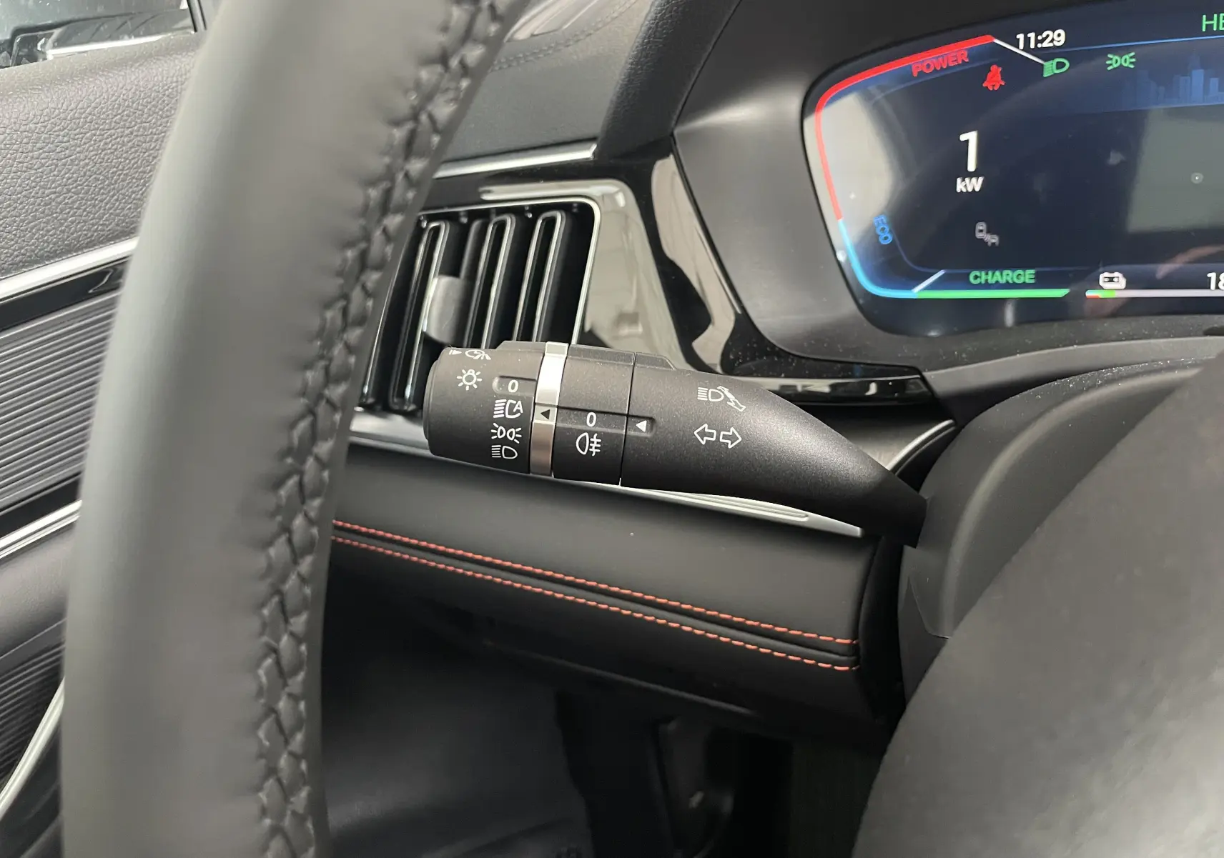 Gros plan sur la manette de commande des phares et clignotants dans l’habitacle noir avec surpiqûres rouges du BYD SEAL U hybride rechargeable.