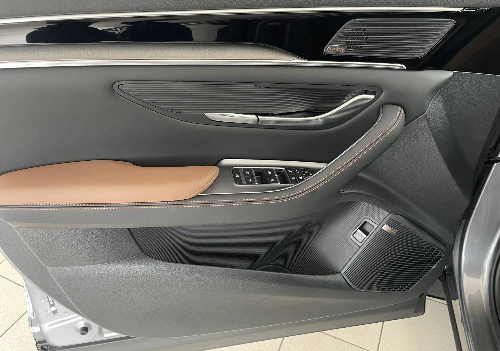 Vue rapprochée de la porte avant gauche du BYD SEAL U 2026 en TIME GREY, avec garniture marron et haut-parleur Infinity.