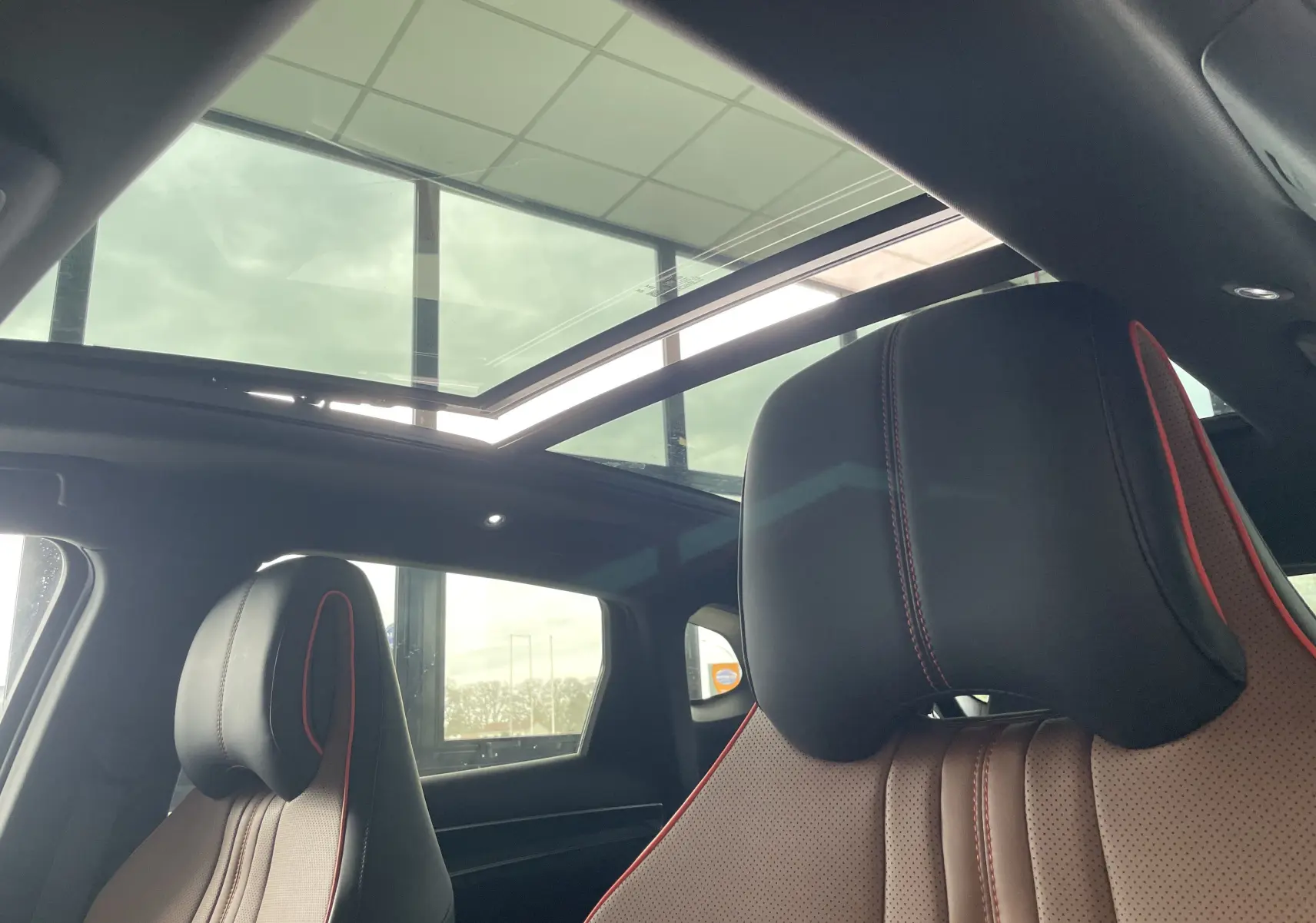 Intérieur du BYD SEAL U 2026 avec toit ouvrant panoramique, sièges en similicuir noir et marron avec surpiqûres rouges.