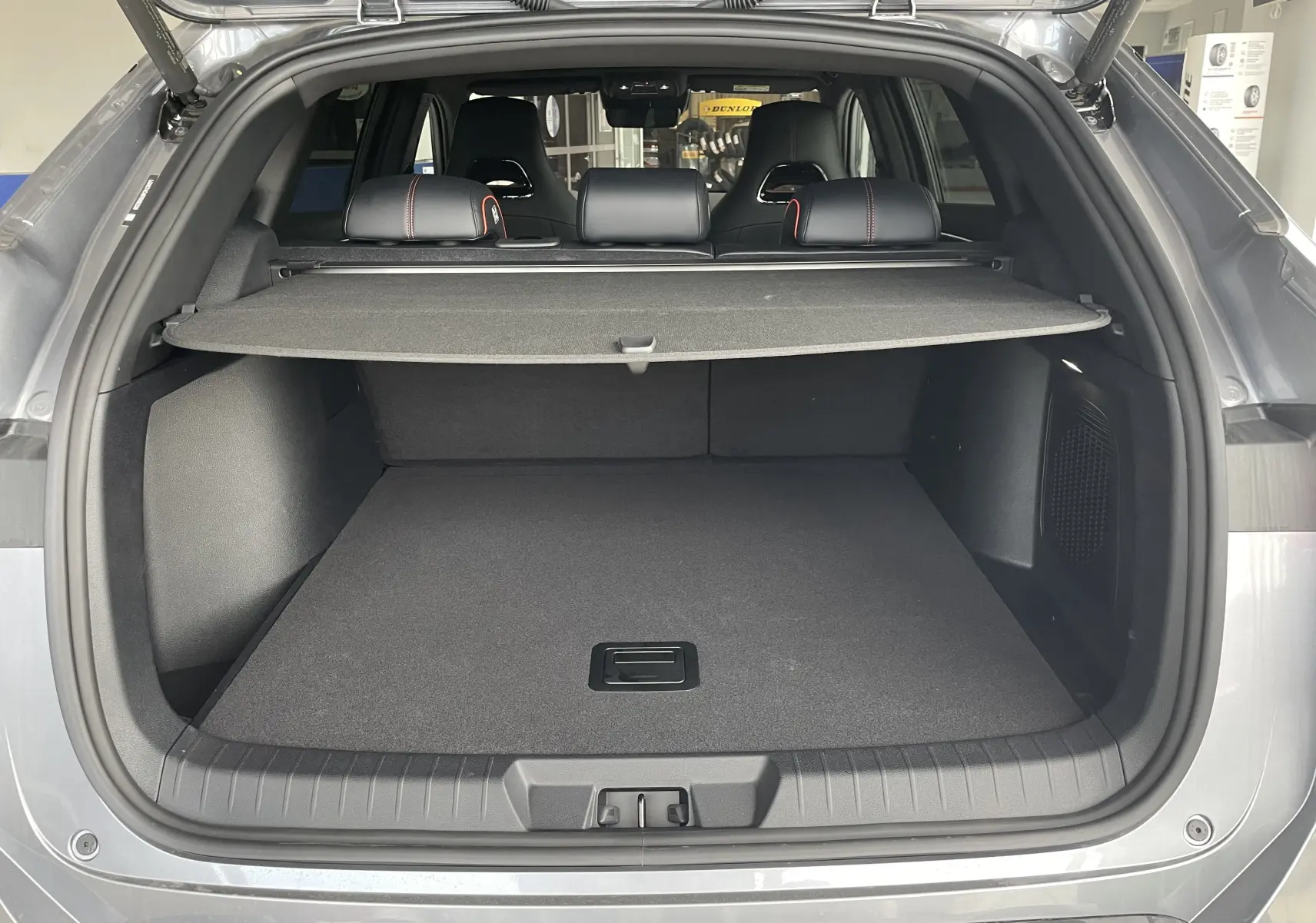 Coffre ouvert vu de l'arrière d'un BYD SEAL U TIME GREY, avec cache-bagages et sièges arrière noirs à surpiqûres rouges.