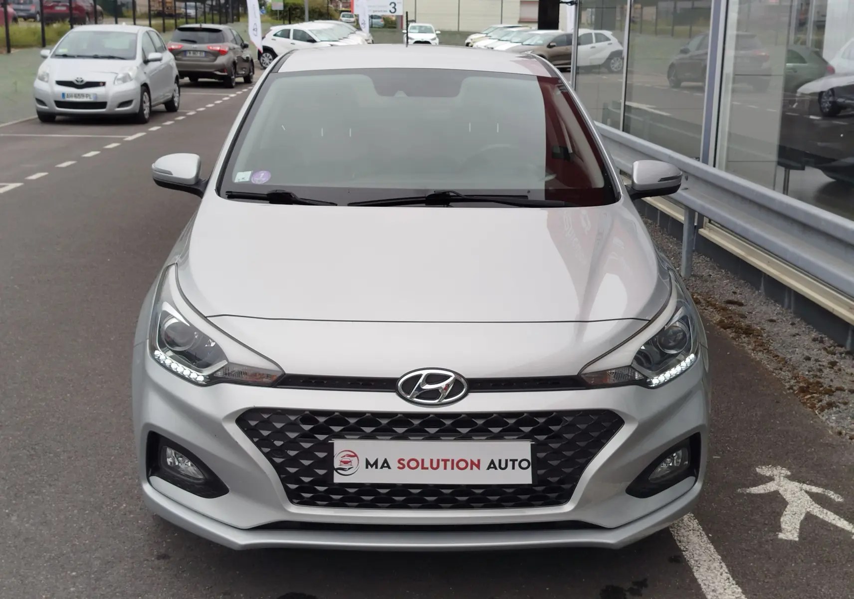 Vue frontale d'une Hyundai i20 2018 en Sleek Silver Métal avec calandre noire et feux LED allumés.