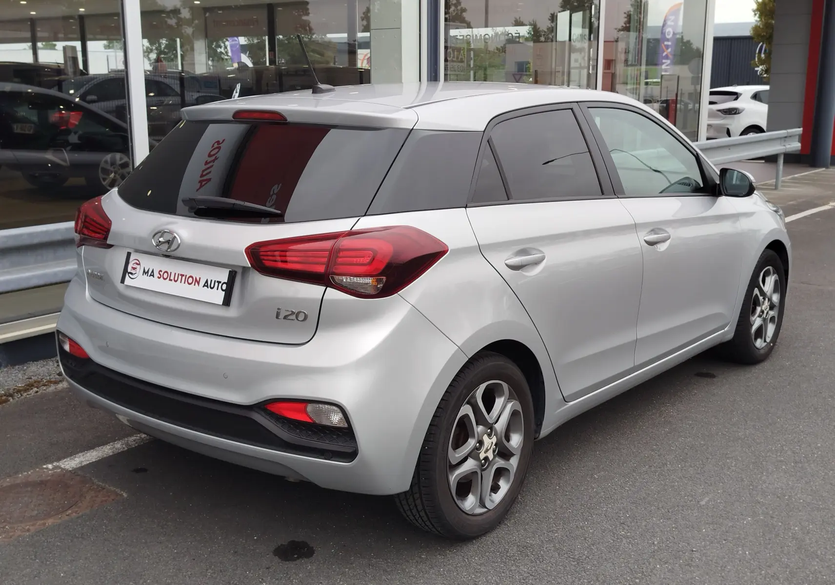 Vue 3/4 arrière droite d'une Hyundai i20 2018 gris argenté avec vitres teintées et jantes alliage.