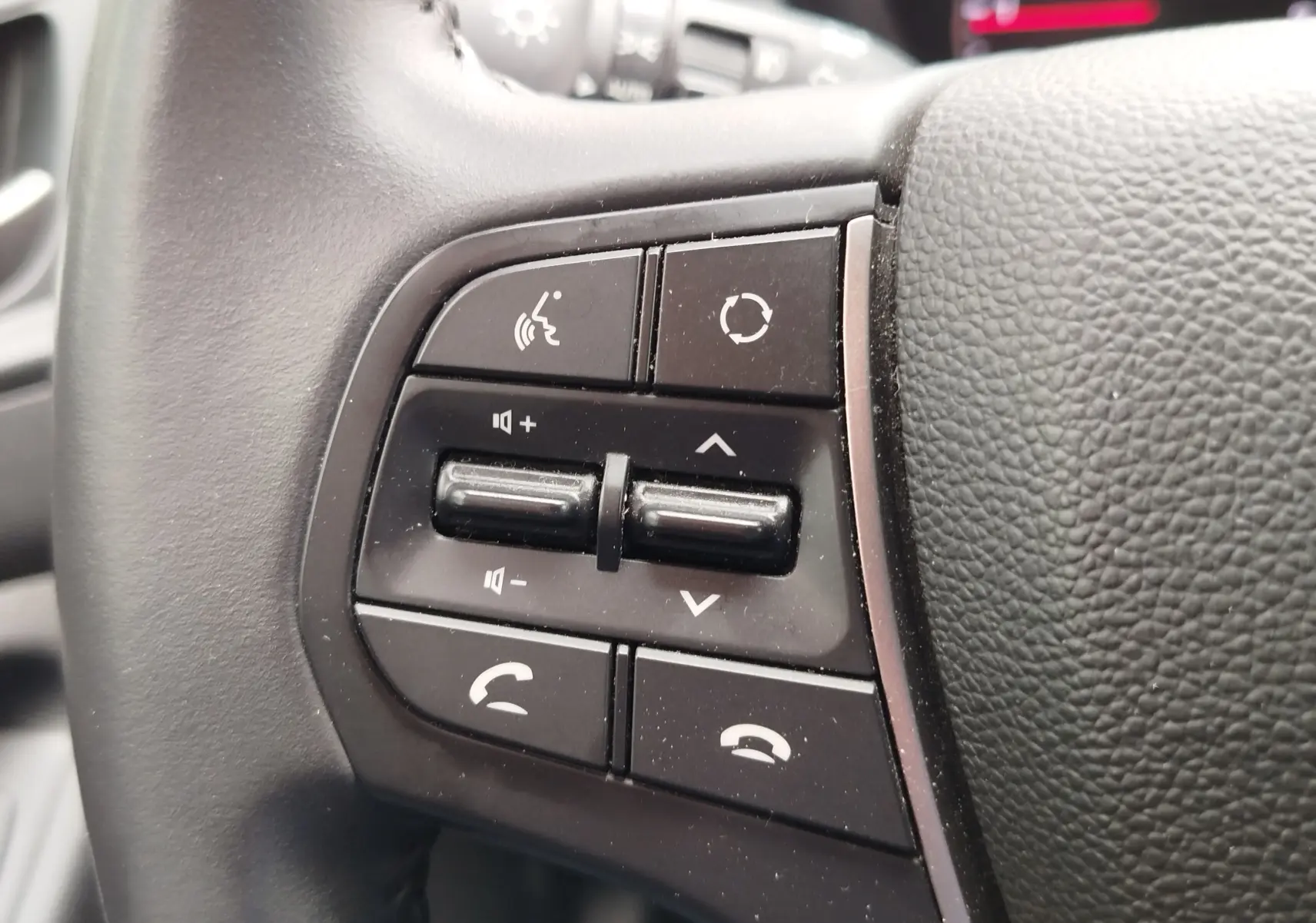 Gros plan sur les commandes multifonctions noires à gauche du volant en cuir noir du Hyundai i20 Sleek Silver 2018.