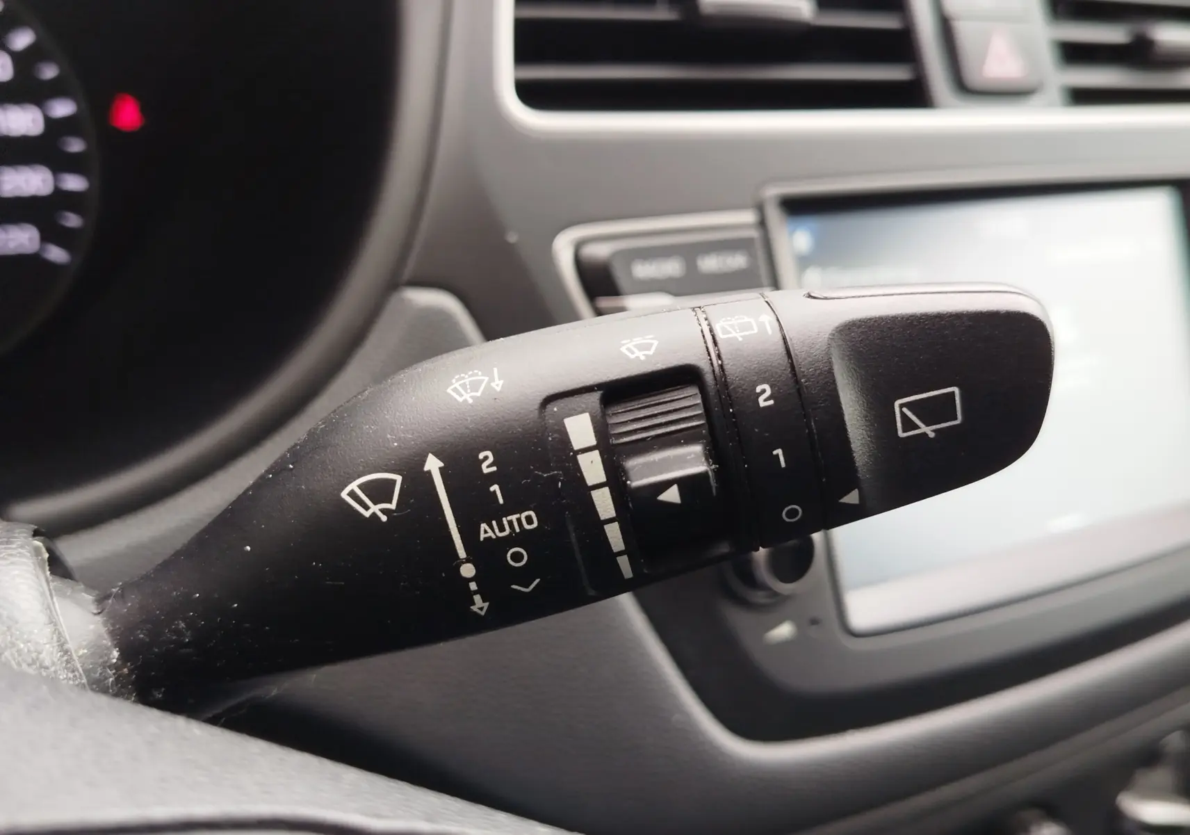 Gros plan sur la commande des essuie-glaces dans l’habitacle gris d’une Hyundai i20 Sleek Silver Métal 2018.