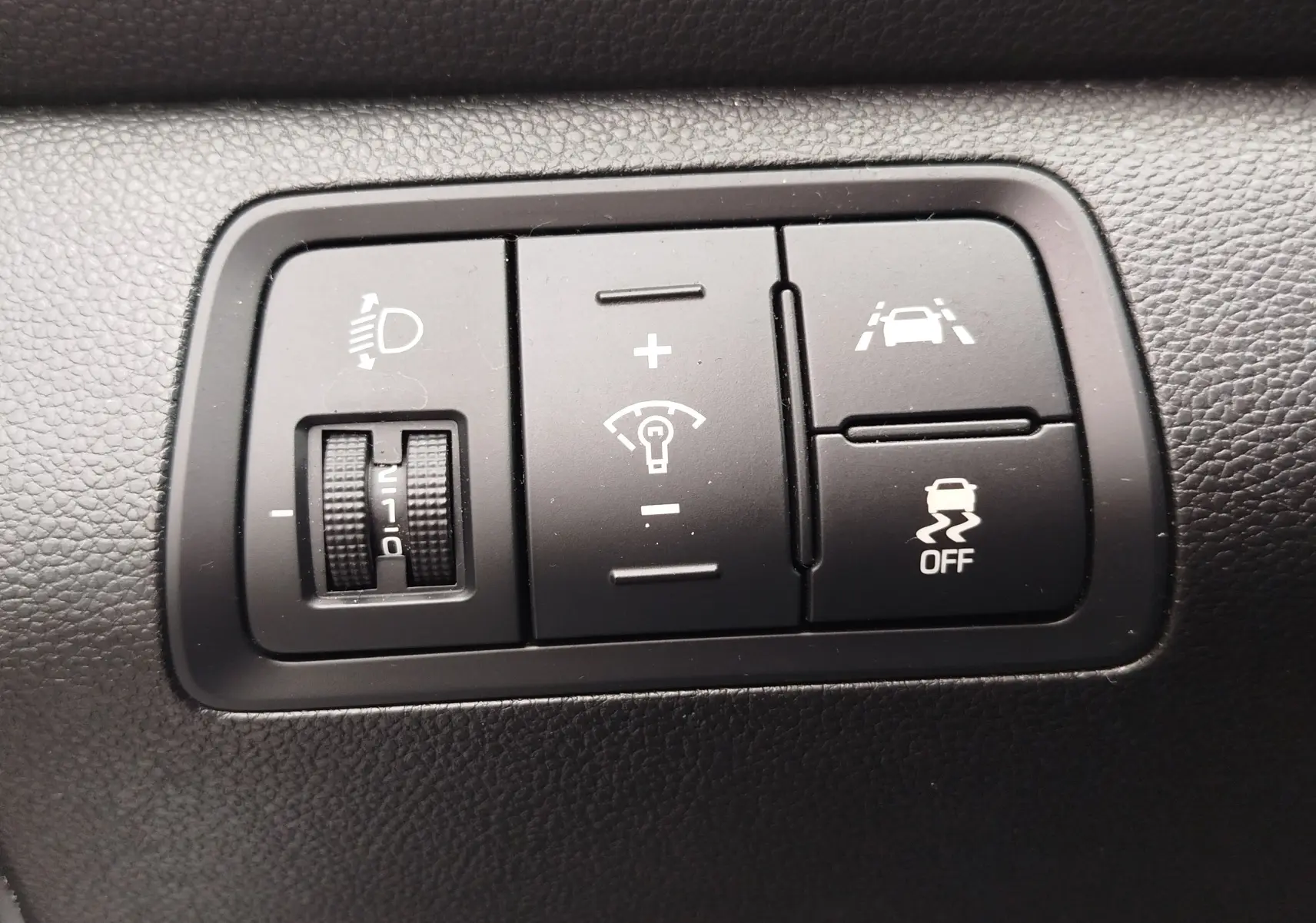 Gros plan sur les commandes noires du tableau de bord de la Hyundai i20 2018, réglage phares et aides à la conduite.