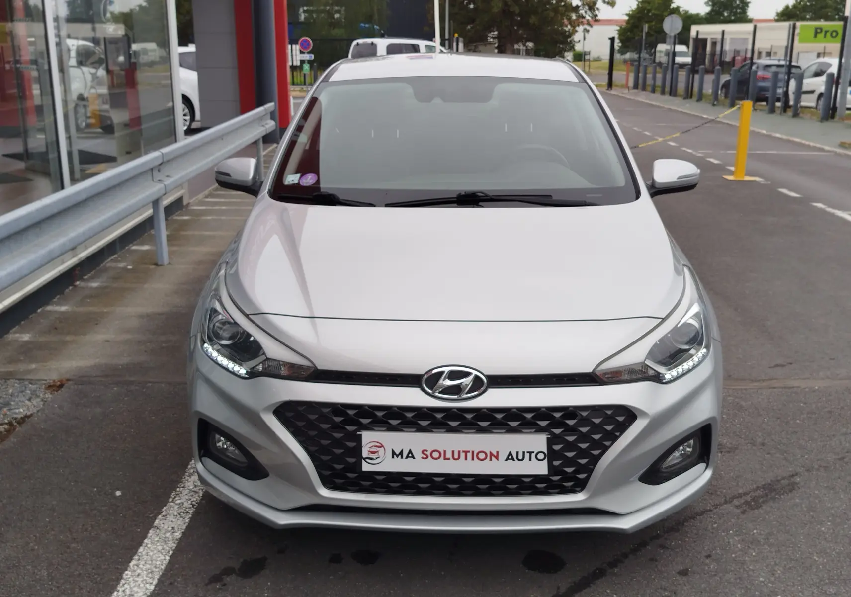 Vue avant d'une Hyundai i20 2018 couleur Sleek Silver Métal avec calandre noire et feux LED allumés.